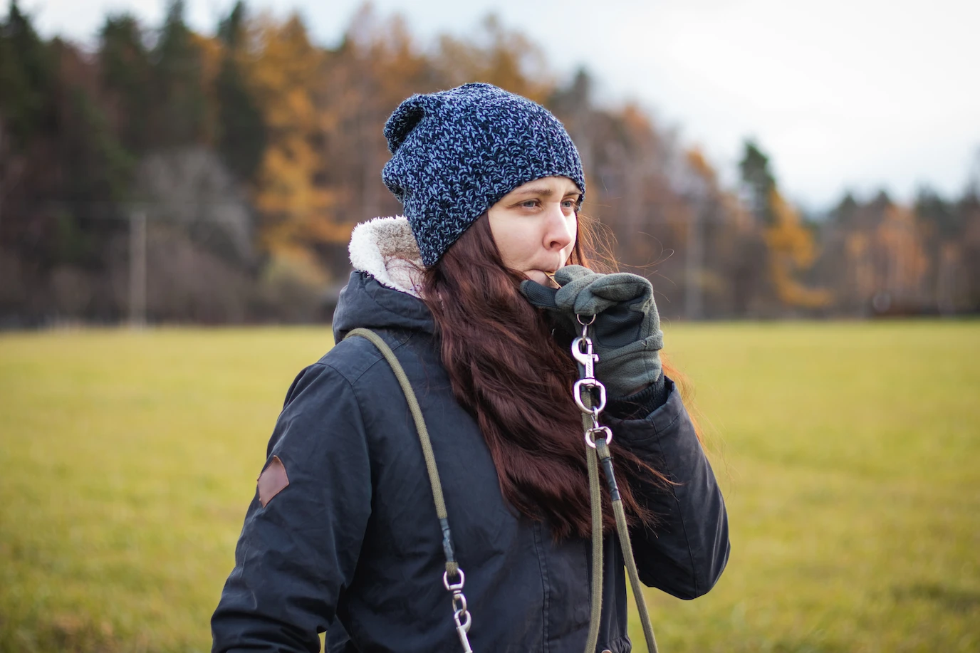 Woman blowing a dog whistle outside