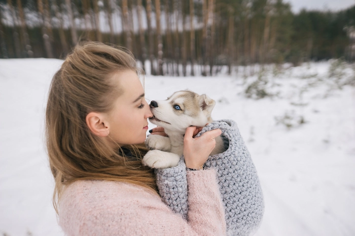 A woman holding a sick  puppy showing cold-like symptoms like sore throat and watery eyes